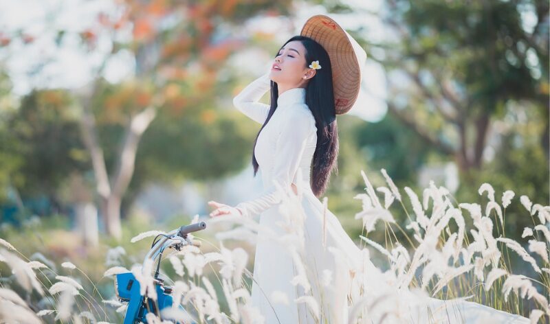 風に揺れる草原の中、目を閉じて深呼吸する女性。誰かの期待から解放され、自分らしさを取り戻す瞬間。