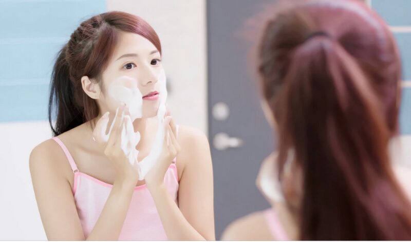 泡立てた洗顔料で顔を洗う女性の写真。洗いすぎによる乾燥や肌のバリア機能低下をイメージしています。