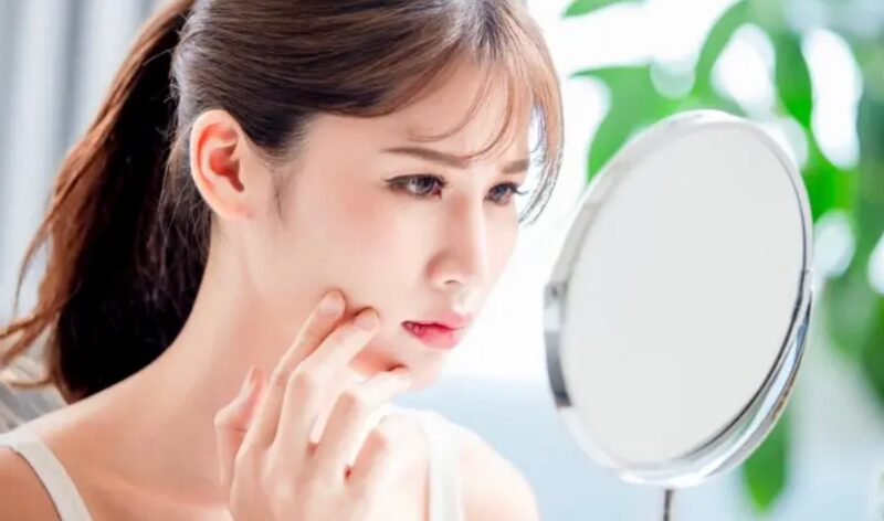 鏡を見ながら肌の乾燥や刺激を気にしている女性の写真。スキンケアの見直しを考えるイメージです。